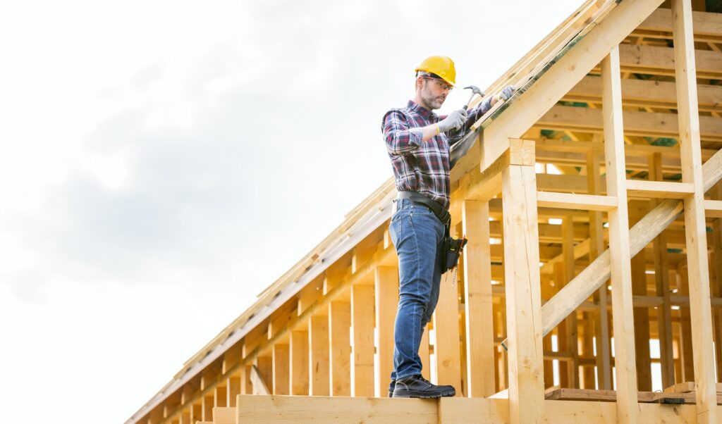 Roofer builder working on roof structure at construction site